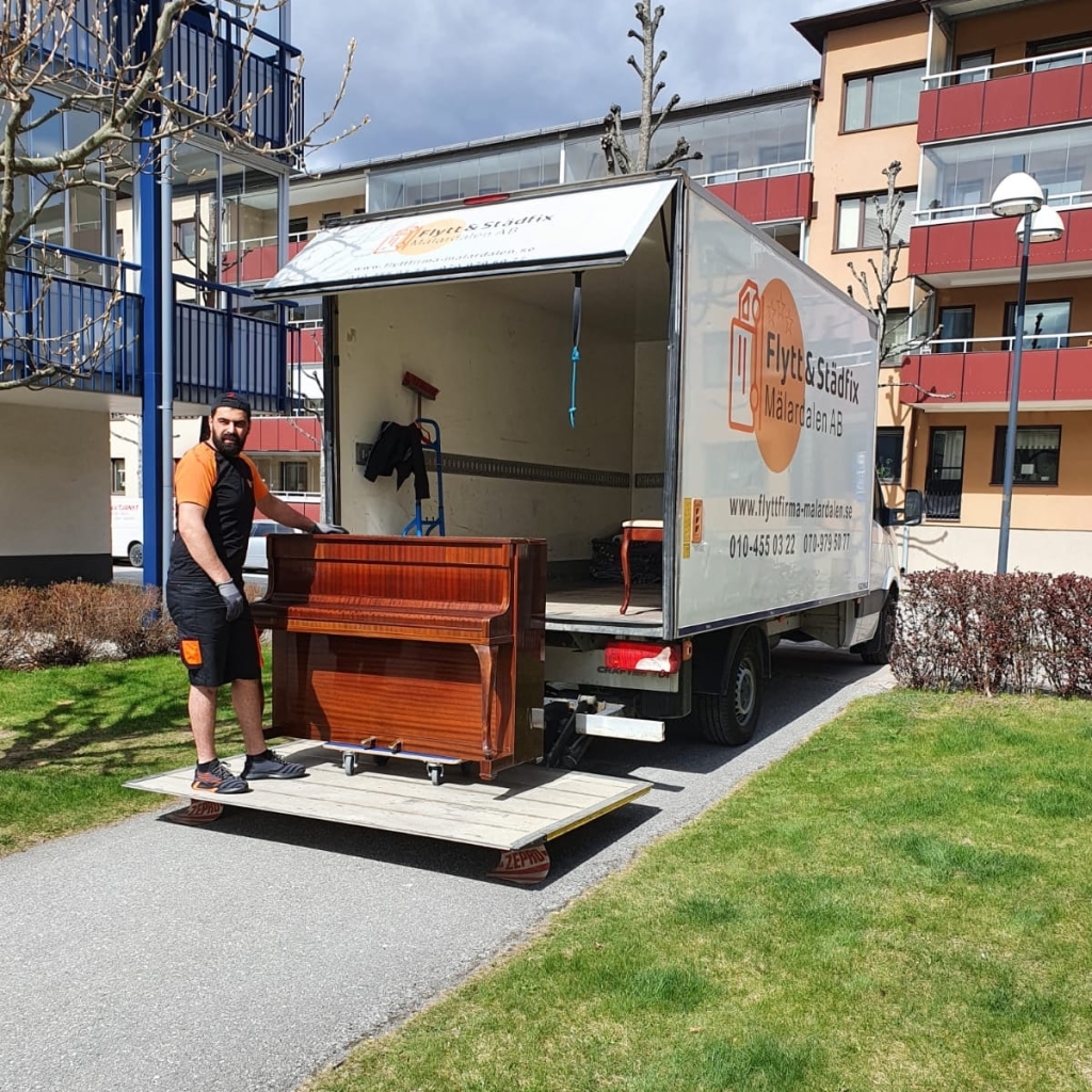 Piano lastas på flyttbil av två personer